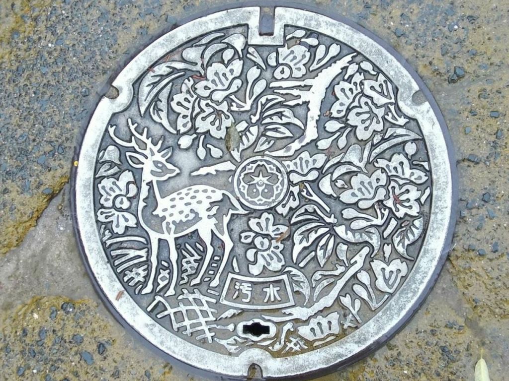 silver manhole in Nara japan showing deer and trees