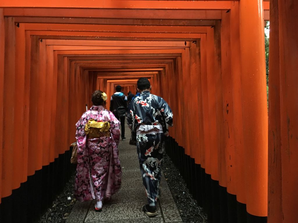 couple in kimino stand between the torii gates at Fushimi Inari shrine