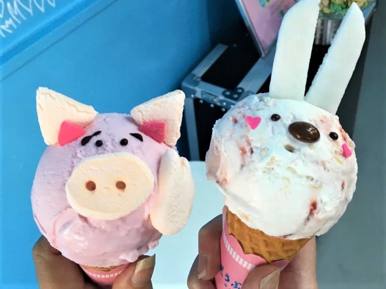 Ice creams from Harajuku in Tokyo. One is a pink ice cream which has had sweets added to turn it into a pig's head, the other one is a white ice cream which has been given rabbit ears.