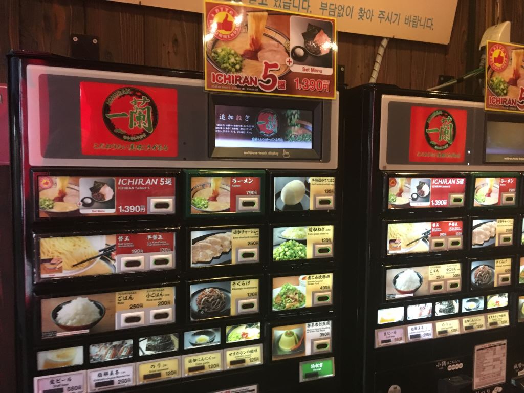 Picture of the famous Ichiran ramen restaurant ordering machine. There are lots of lit up buttons with pictures of ramen dishes, rice, pork slices and other things you can order in the restaurant.