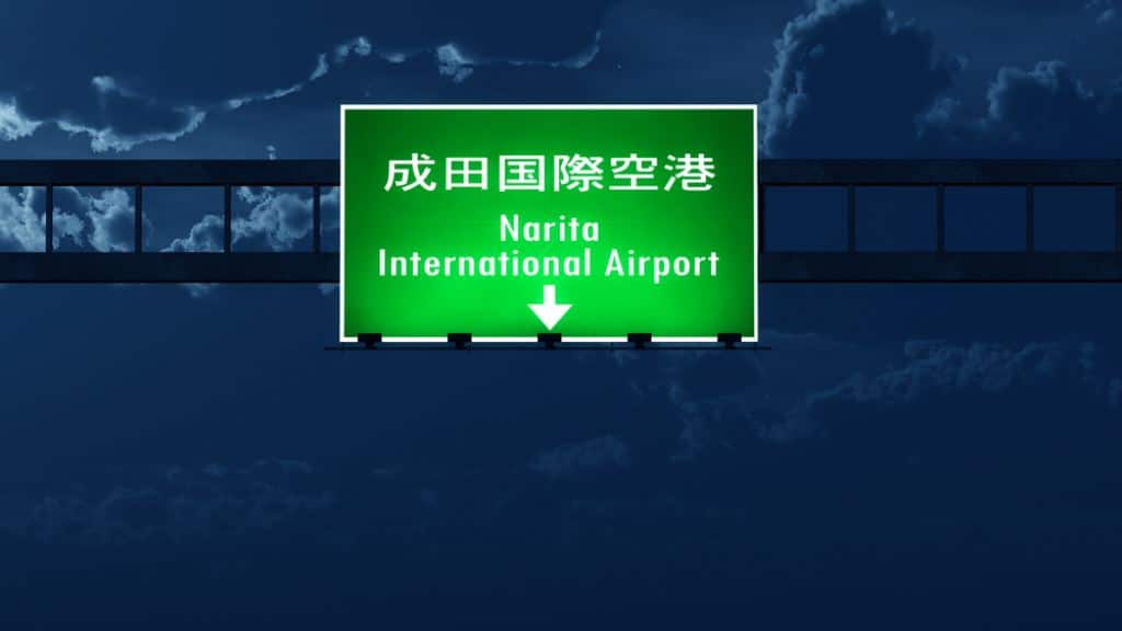 Illuminated green sign that reads Narita International Airport against a night sky