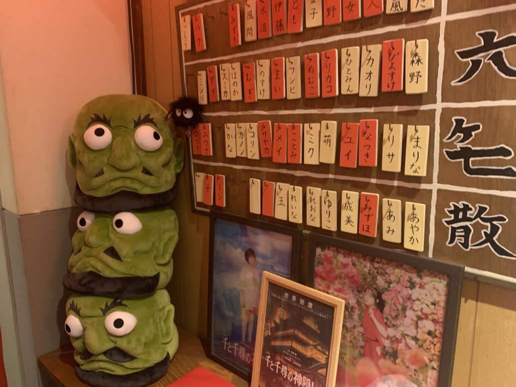 Picture from inside Kodama Ghibli-inspired cafe in Nagoya. IT shoes three green heads stacked on top of each - these are the Kashira from the famous Ghibli film Spirited Away 