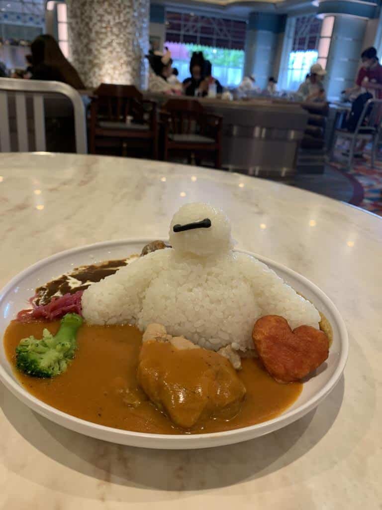 Baymax Curry at Tokyo Disneyland. The rice is shaped like the character Baymax. He's sitting in a lake of curry with a heart shaped vegetable next to him.