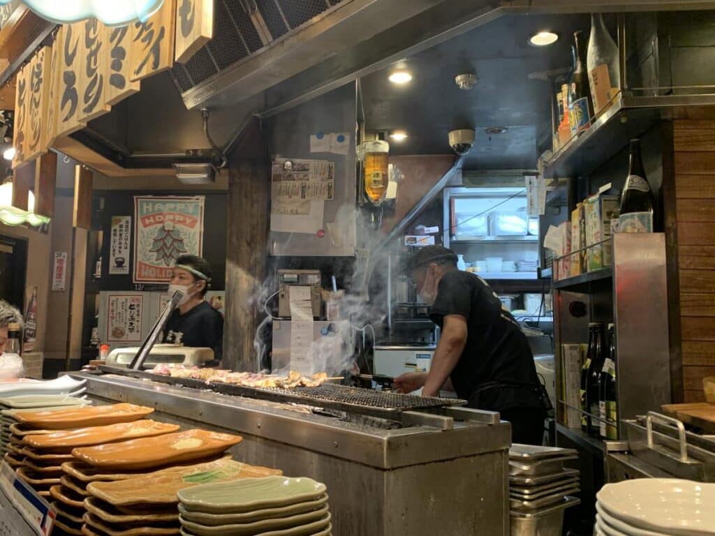 Two chefs cook yakitori over a smokey grill in Tokyo