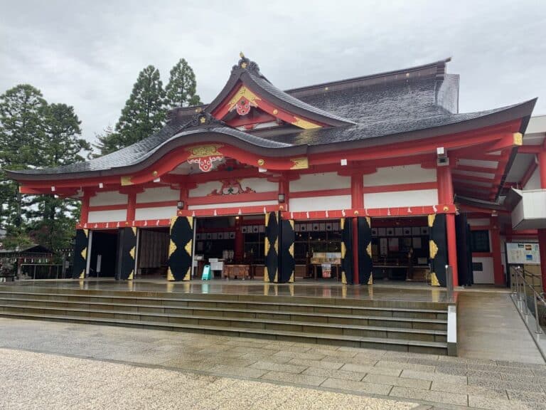 Front of the main building at Hie Shrine in Toyama. It has a pointed roof, and scarlet and gold decorations.