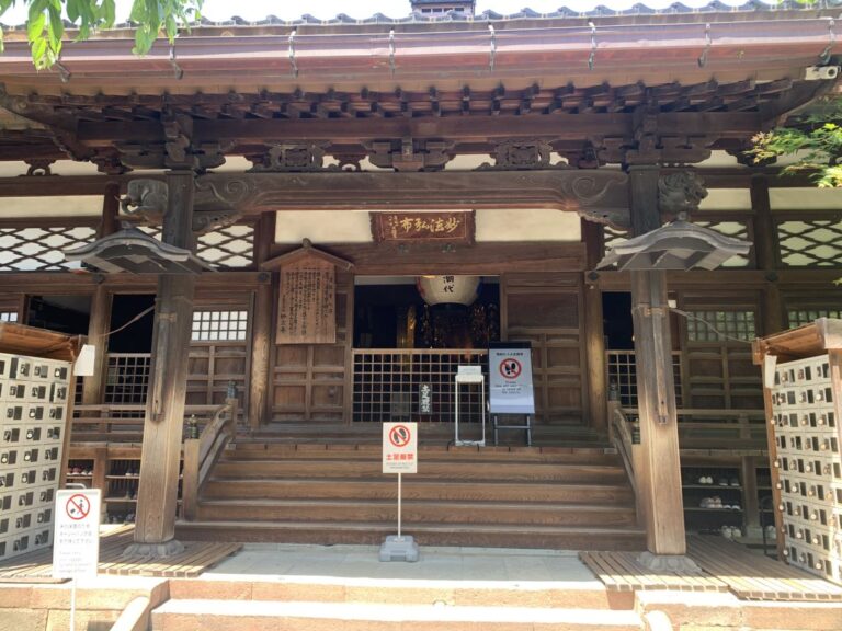 Front view of Kanazaw'as Ninja Tempe with wooden steps leading up to the main later. Many signs tell you to remove your shoes.