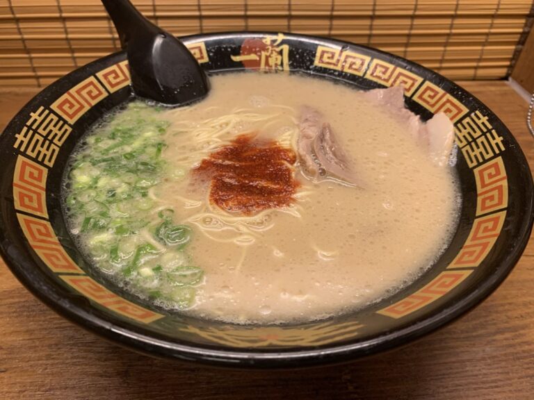 bowl of creamy tonkatsu ramen at Ichiran in Japan. topped with green onions, red sauce and pork slices