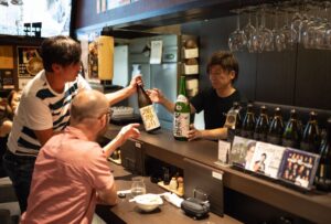 bar person in Sendai shows sake bottles to customers