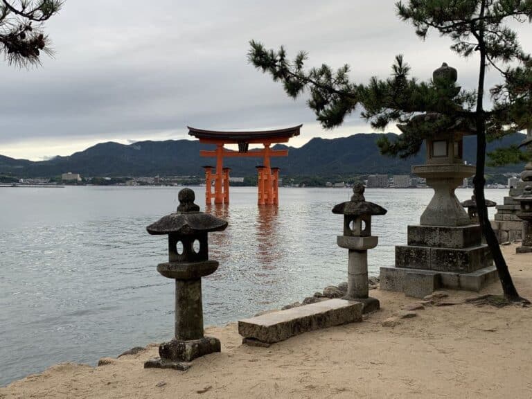 Miyajima torii gate photographed from th eshore with stone lanterns in front of it