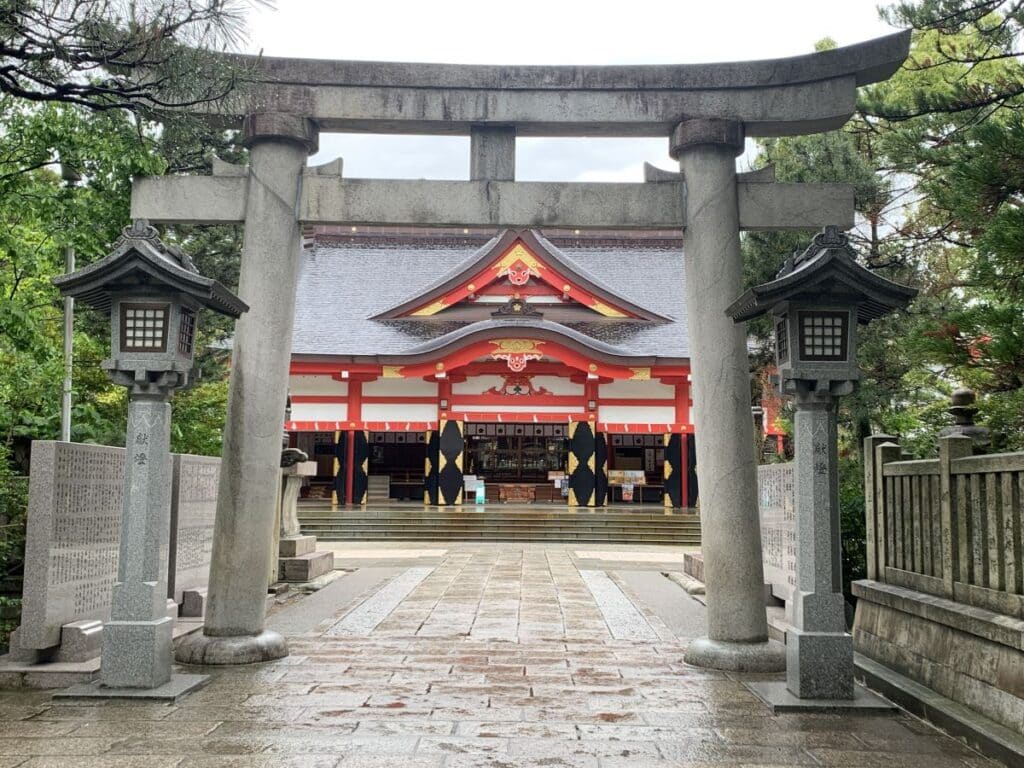 the red and gold front of Hie Shrine in Toyama with a stone concrete gate in front.