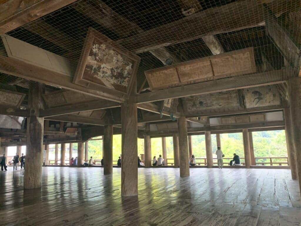 Interior of Hokuku showing polished wooden floors, paintings, wooden columns hold up the structure but the sides are completely open.