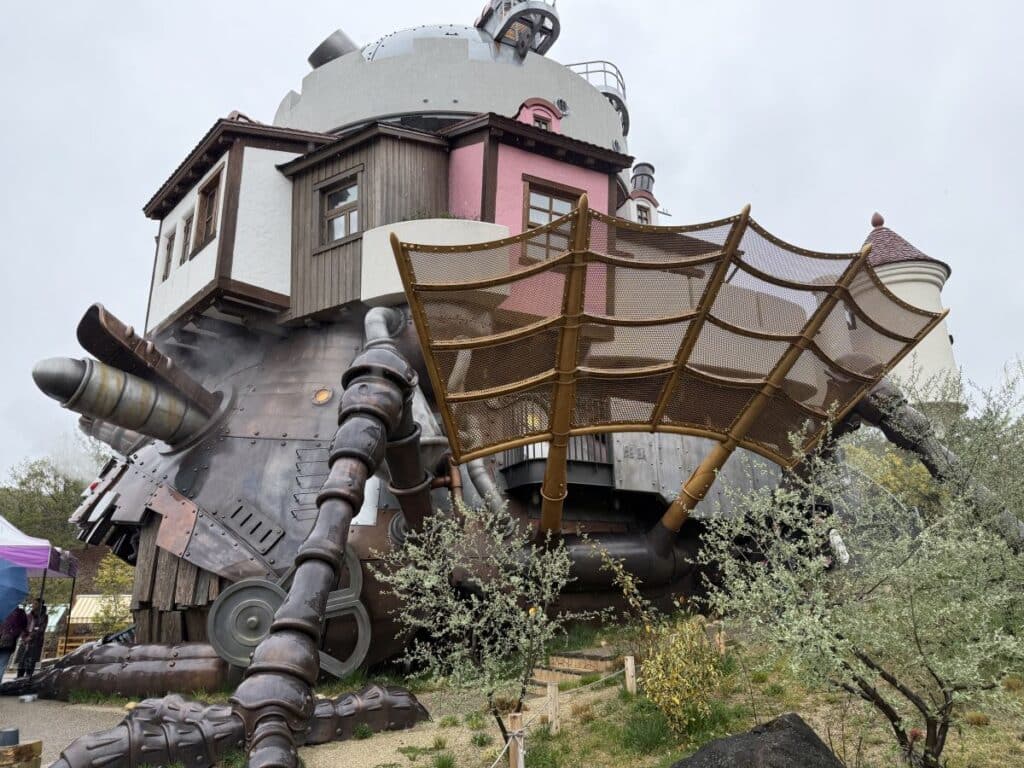 Close up view of the exterior of Howl's Moving Castle showing the spider like legs, and steam coming out. 