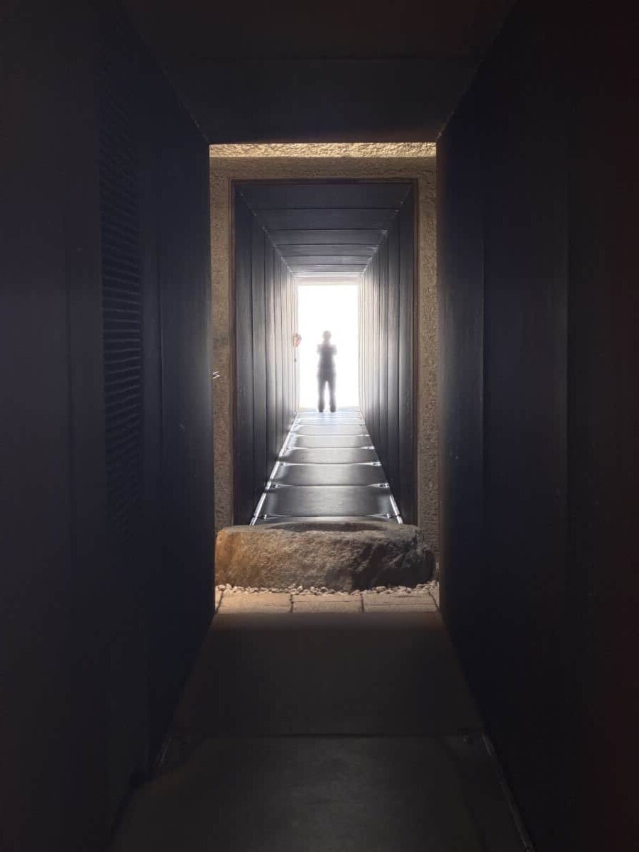 View down one of the tunnel artworks at Enoura Observatory - a person stands silhouetted at the end