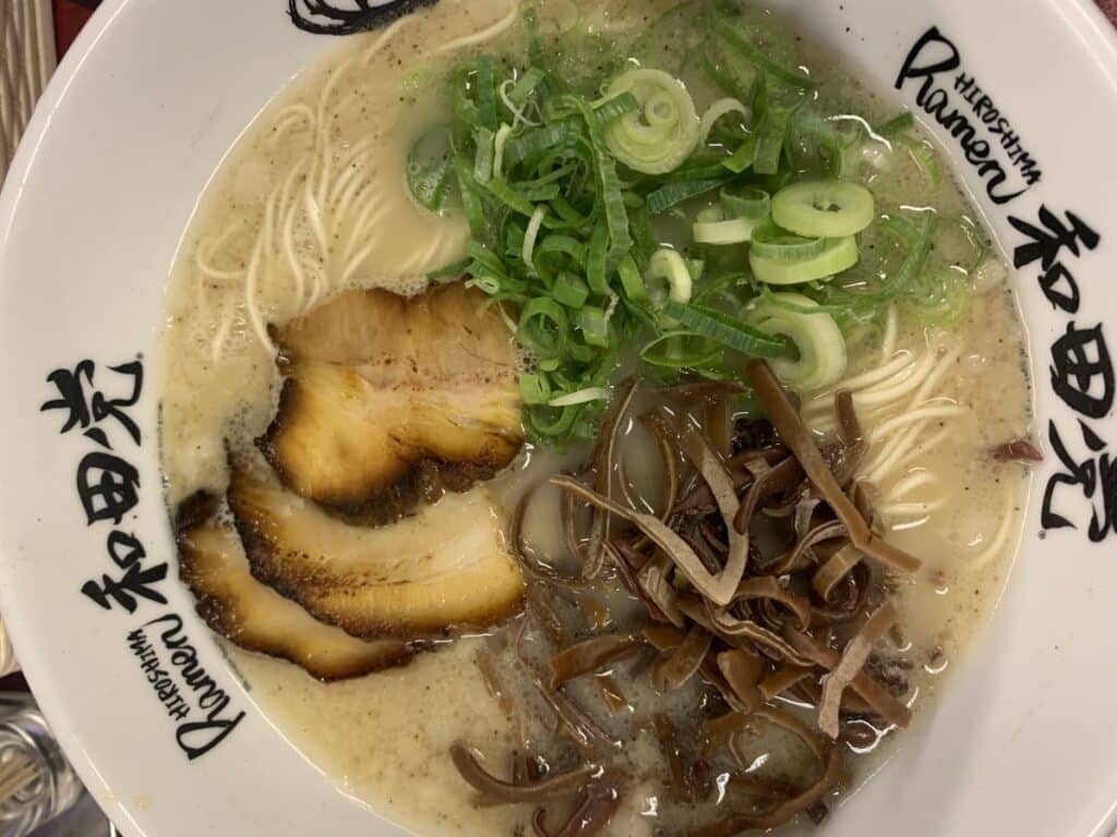 Bowl of ramen loaded with spring onions and sea vegetables, pork and noodles