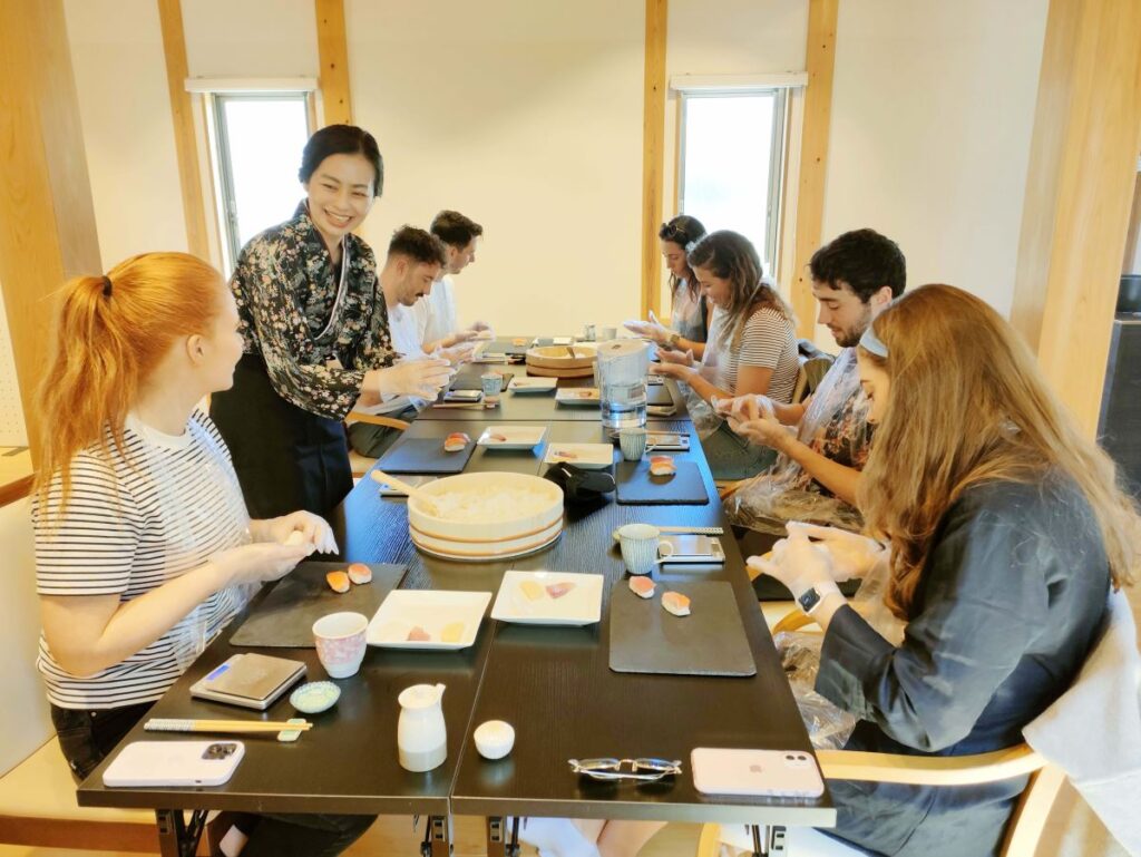 Tourists sit at a table making sushi in Kyoto