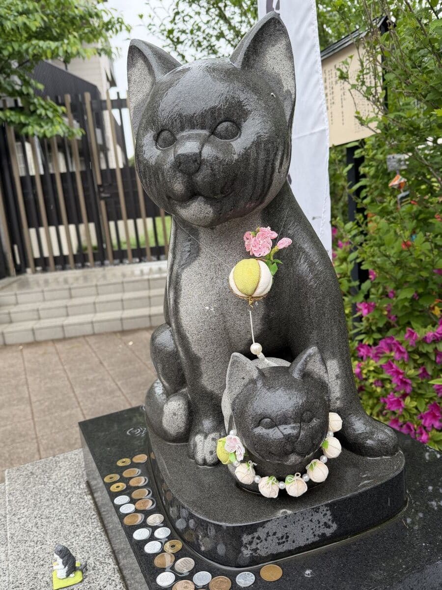 Cat statues at Komagome Shrine in Tokyo - a big cat sits next to a kitten.