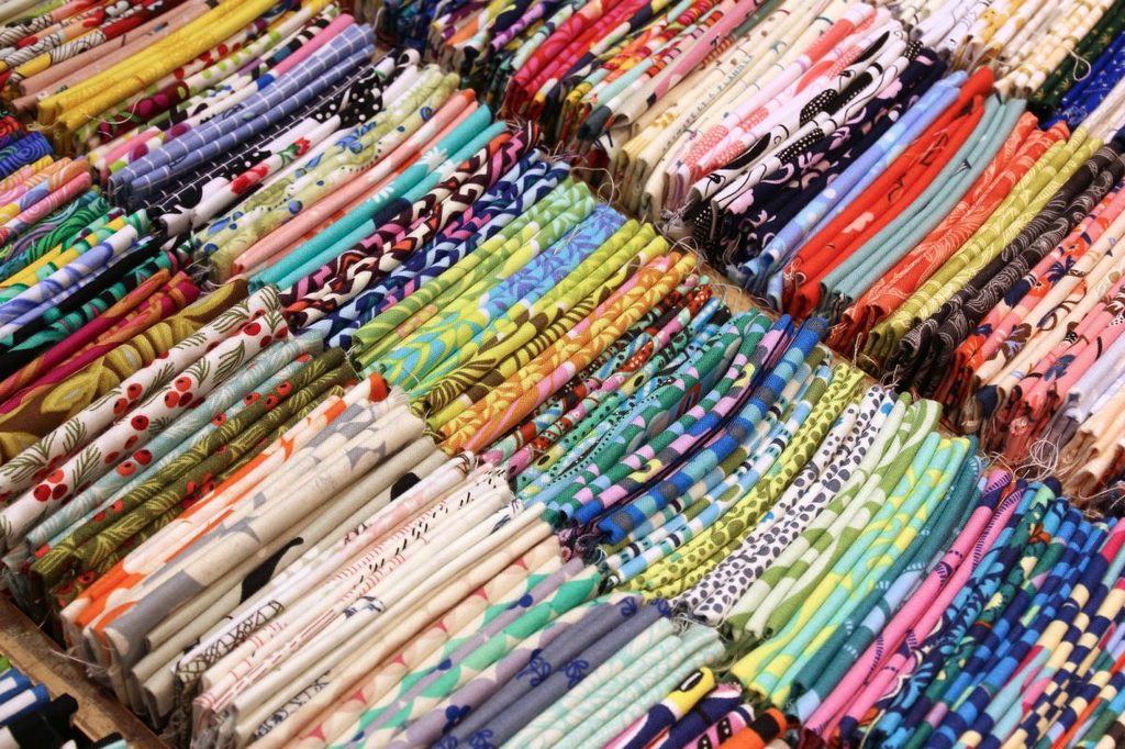 Tenugui cloths lined up for sale by colour in a shop in Japan