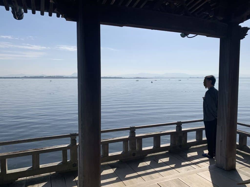 man stands looking at the water at Ukimido Shrine