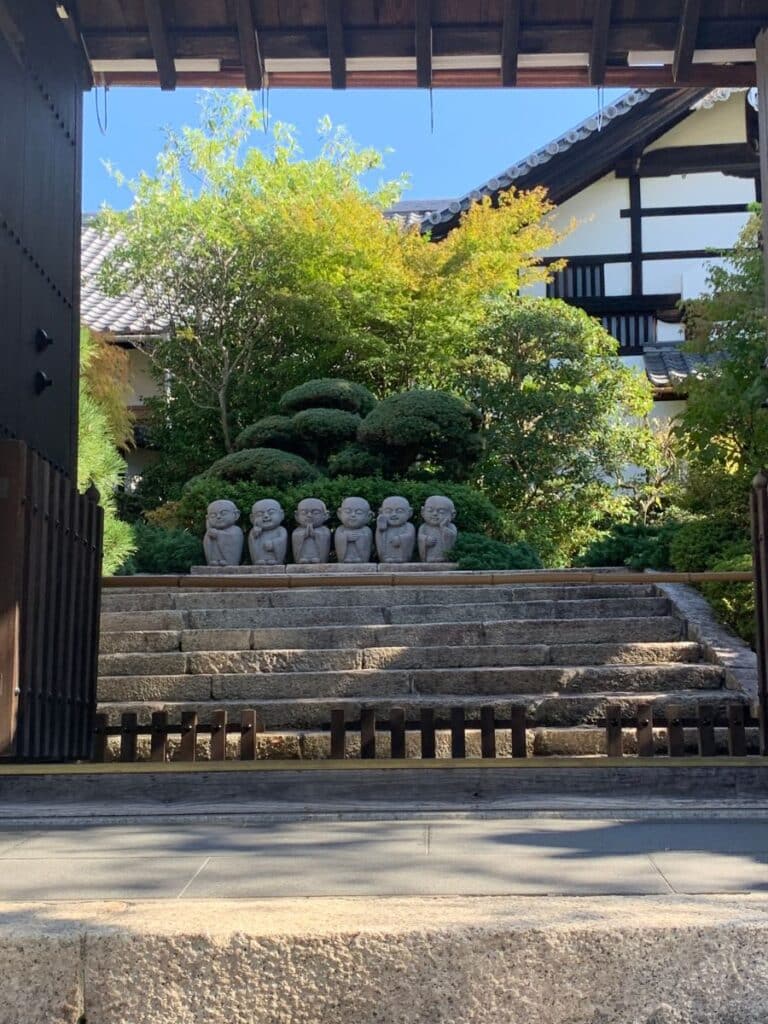 Five jizo statues with different hand and facial positions stand at the top of a set of steps