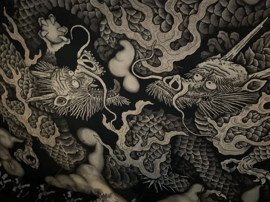 Black and white painting of two dragons on the ceiling at Kennin-ji. One of the dragons holds a globe in his claws