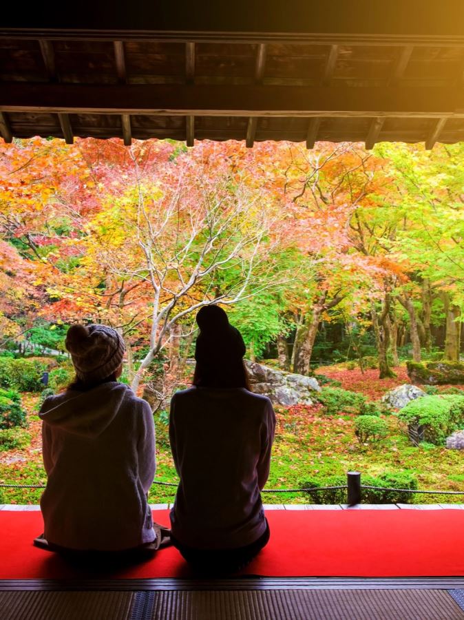 Women in wooly hats look at the leaves in Kyoto