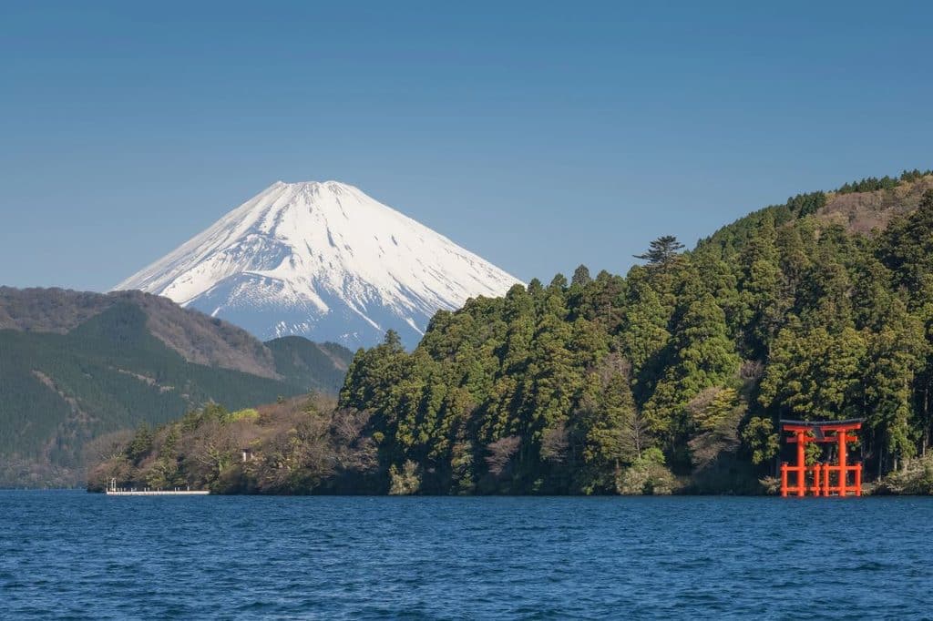 View of the snow capped cone of Mount Fuji above Lake Aishi - the red Hakone Shrine is off to the right. 