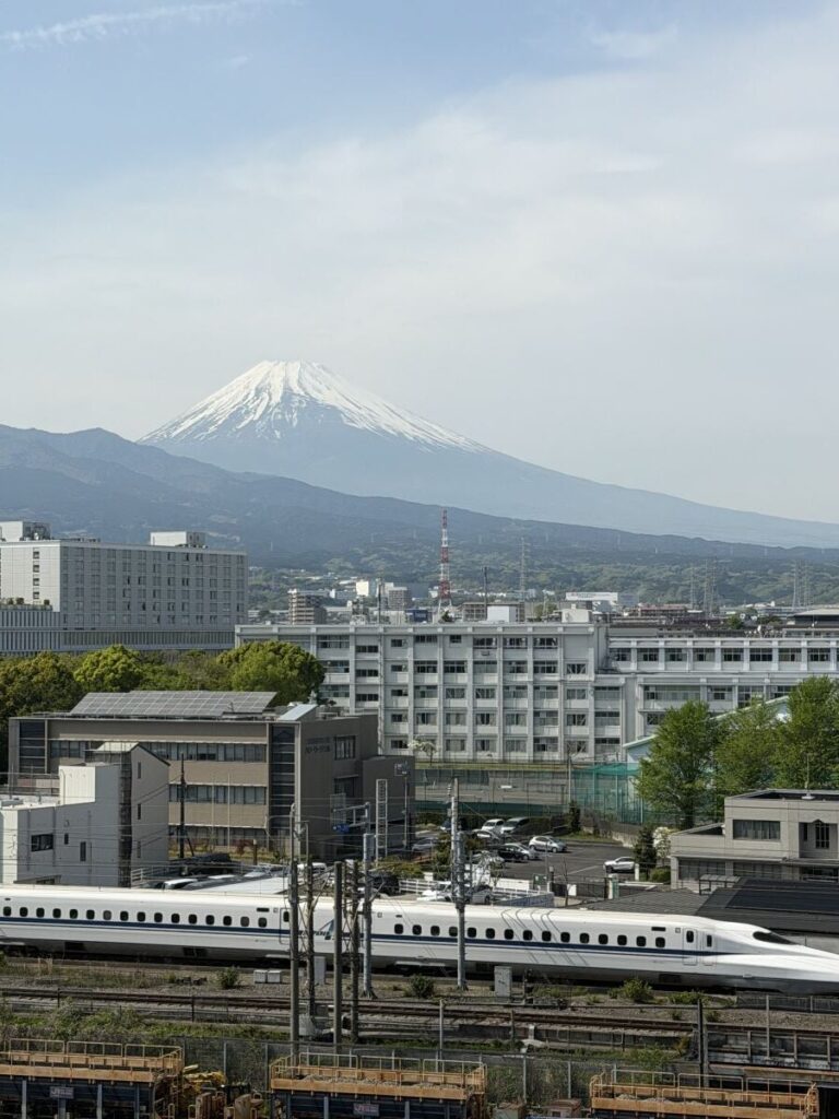 Mount Fuji towers over Mishima - a bullet train speeds past in the bottom of the picture