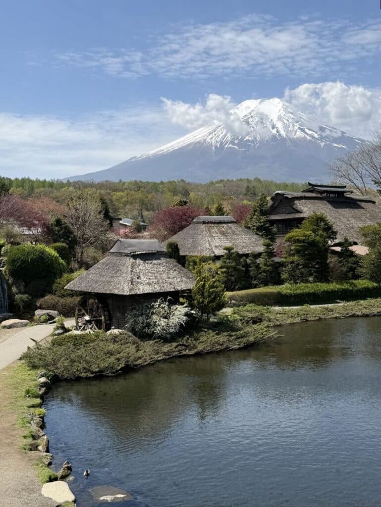 Mount Fuji looms over thatched houses in the Oshino Hakkai museum area. 