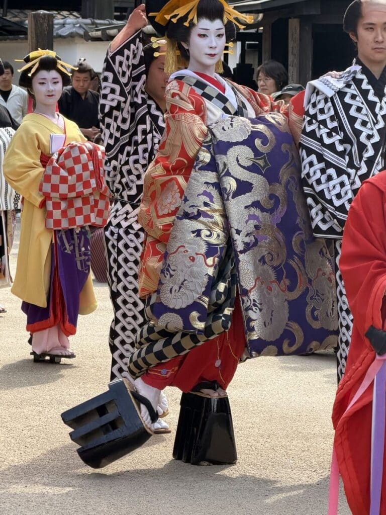 Oiran at Edo Wonderland twists her foot to the side as part of the elaborate figure of 8 step. she wears huge black platform shoes